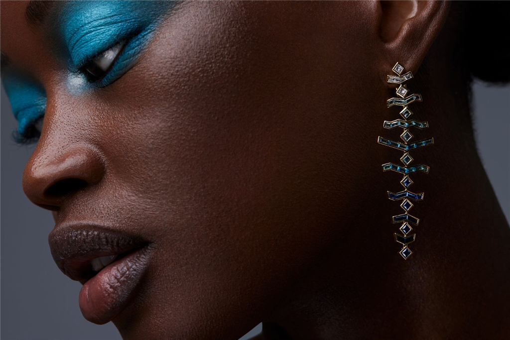 model wearing dangling gold and shades of blue gem earrings.