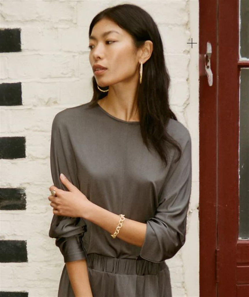 Model wearing gold chain link bracelet and gold hoop earrings