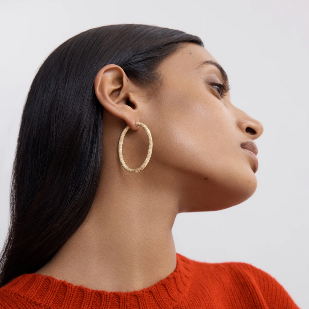 model wearing large oval gold hoop earrings 