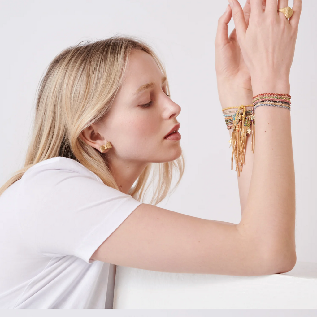 Model wearing multiple silk rope bracelets with gold charms