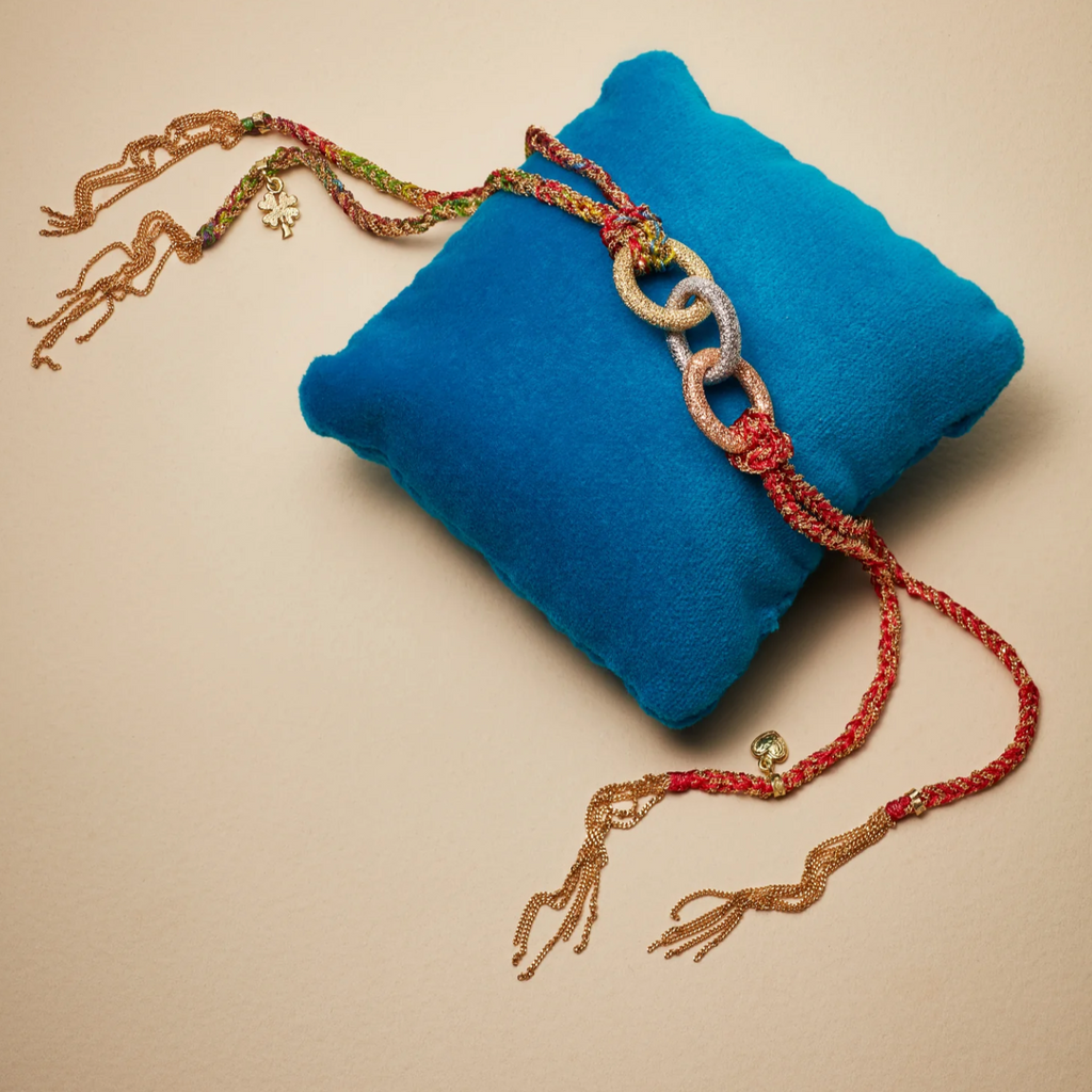 Carolina Bucci lucky bracelets with gold rings on a bue satin pillow
