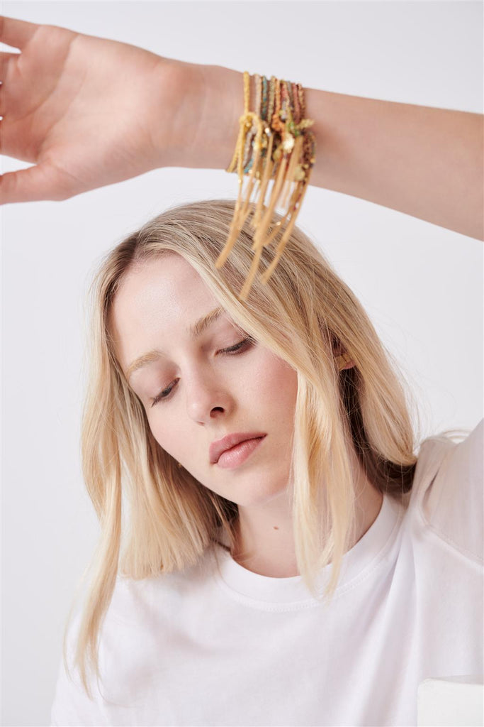 model wearing multiple rope silk bracelets with gold charms