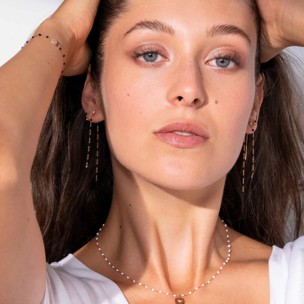 model wearing gold earrings with small black beads