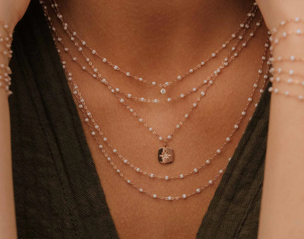 model wearing multiple gold and white beaded necklaces