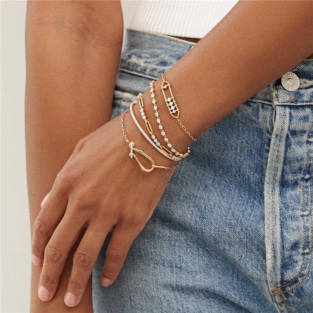 model wearing five gold bracelets with diamonds