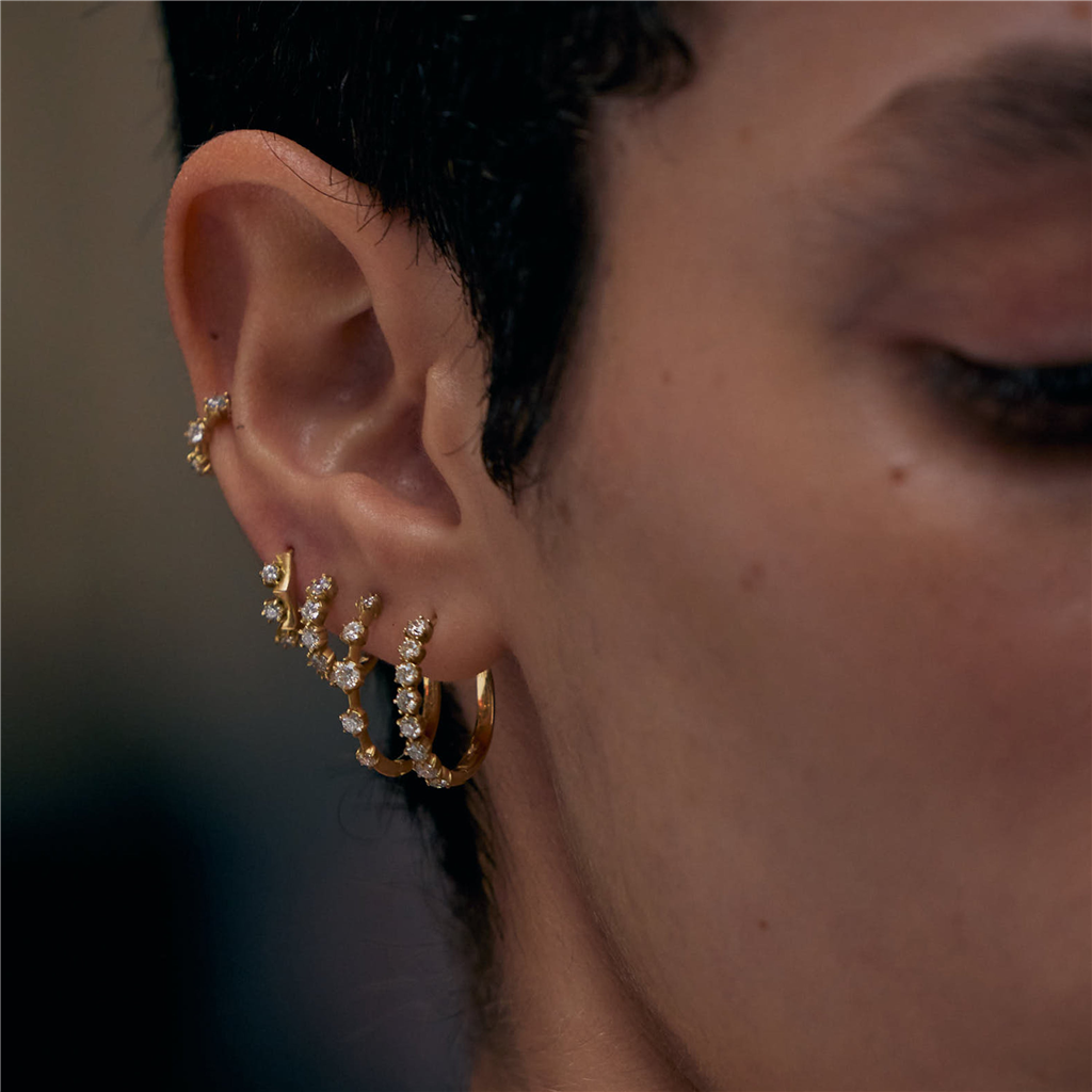 model wearing multiple gold and diamond hoop earrings