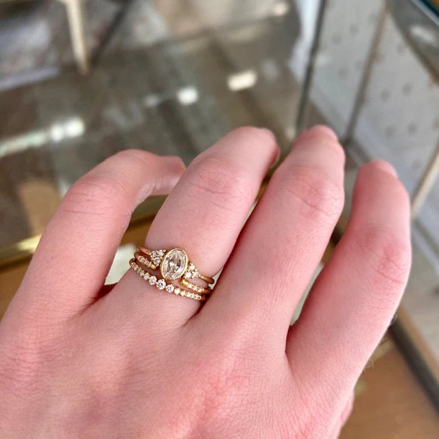 model wearing oval diamond ring with 2 diamond and gold bands