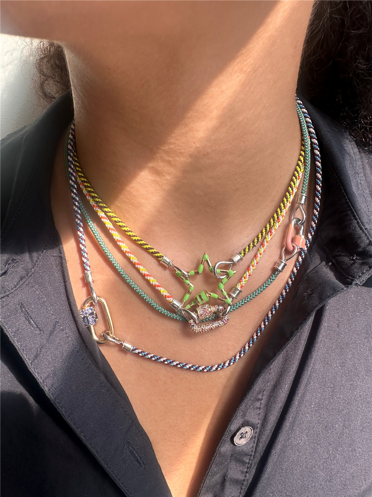 model wearing 4 string chord necklaces with varying gold and silver pendant locks