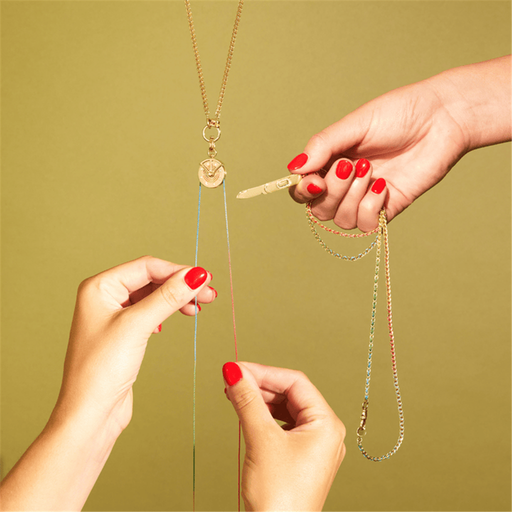 Model with red nails holding gold pocket knife
