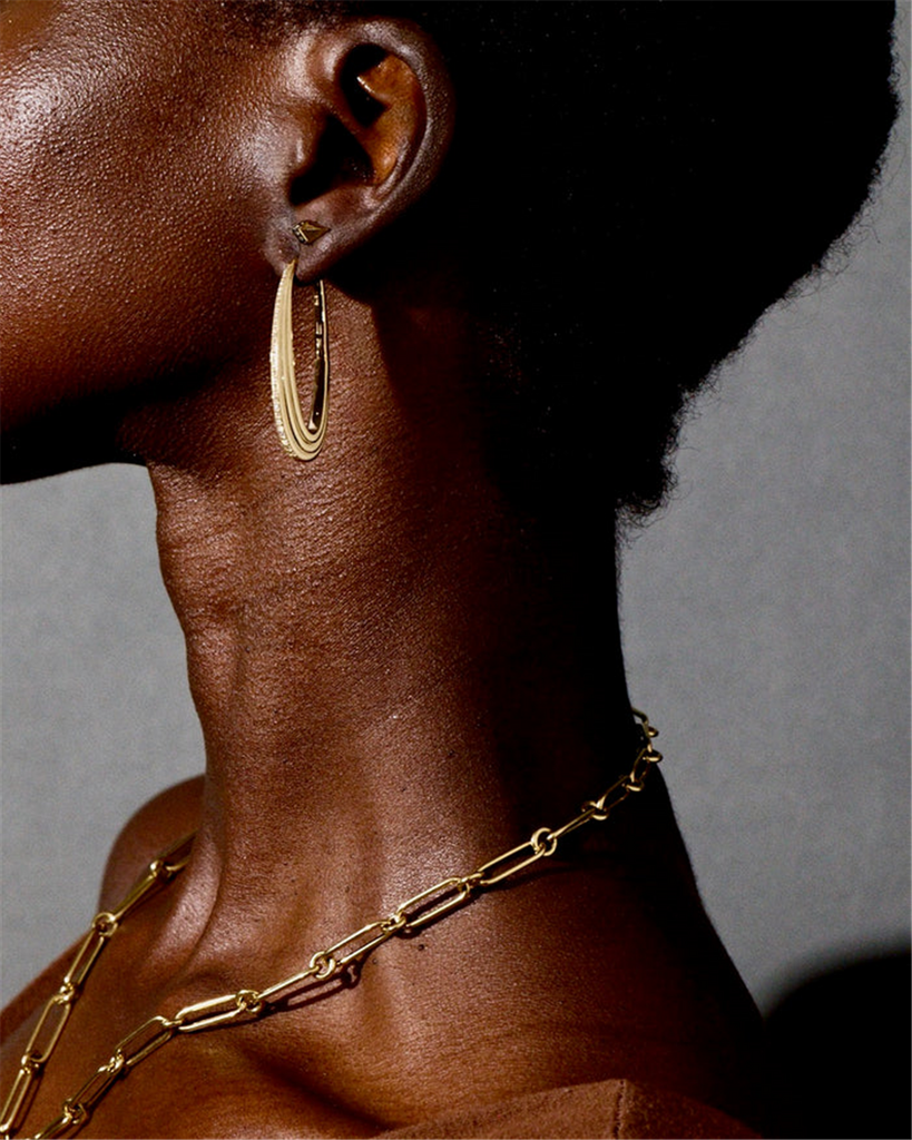 model wearing gold hoop earrings with diamonds on edges and a gold chain necklace