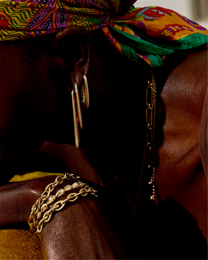 Model wearing 3 hoope gold earrings with diamond edges and gold chain necklace and bracelets