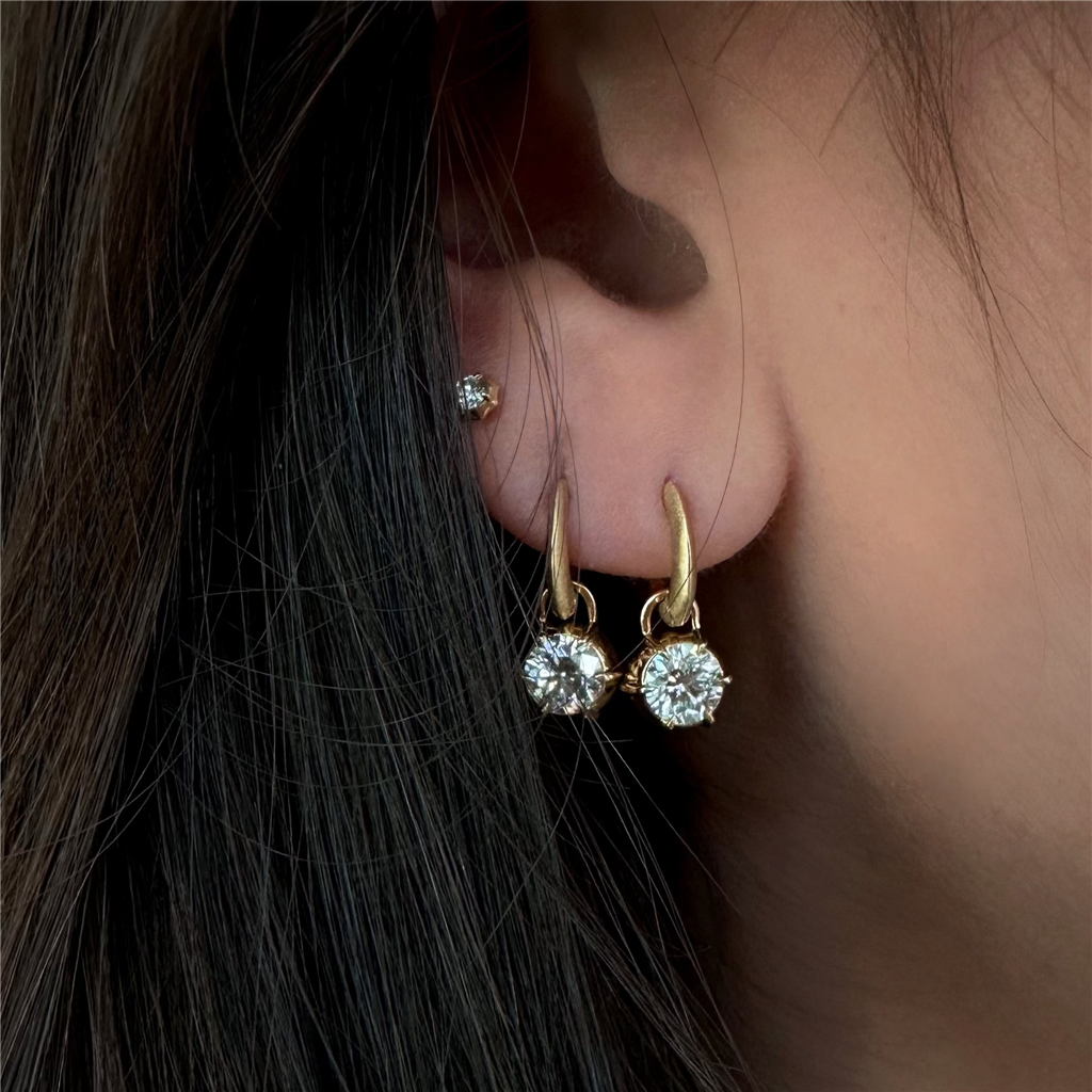 model wears 2 diamond drop earrings and one diamond stud
